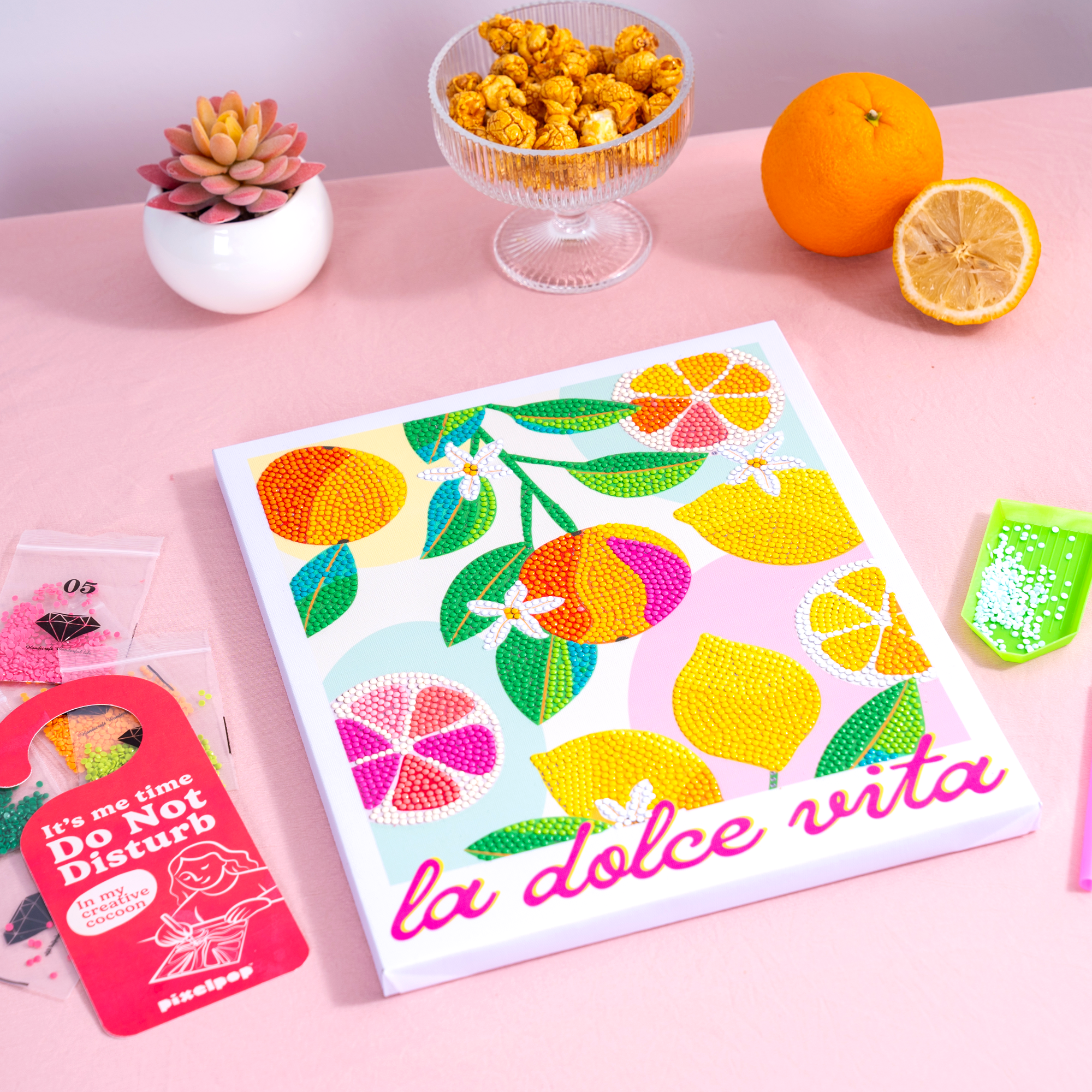 Colorful lemon-themed placemat with 'la dolce vita' text on a pink surface with decorative items.