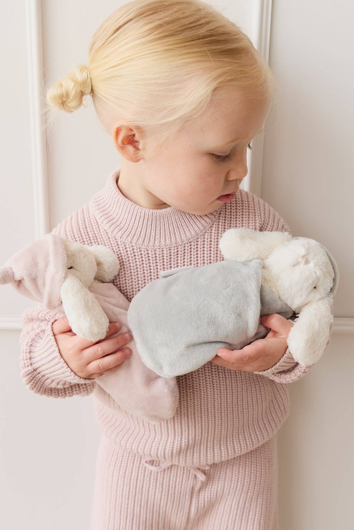 Child holding plush toys against a white background