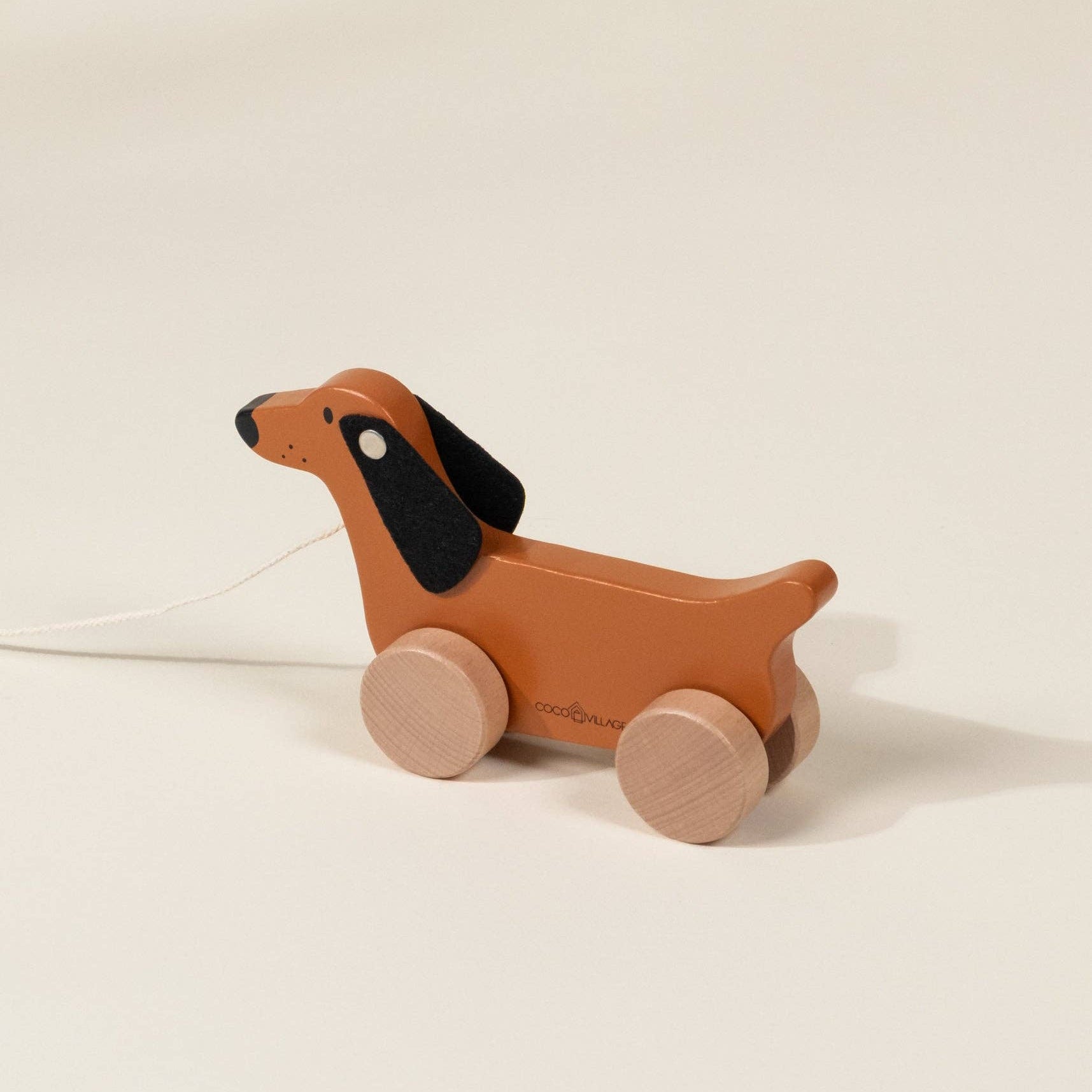 Wooden dachshund pull toy on a beige background