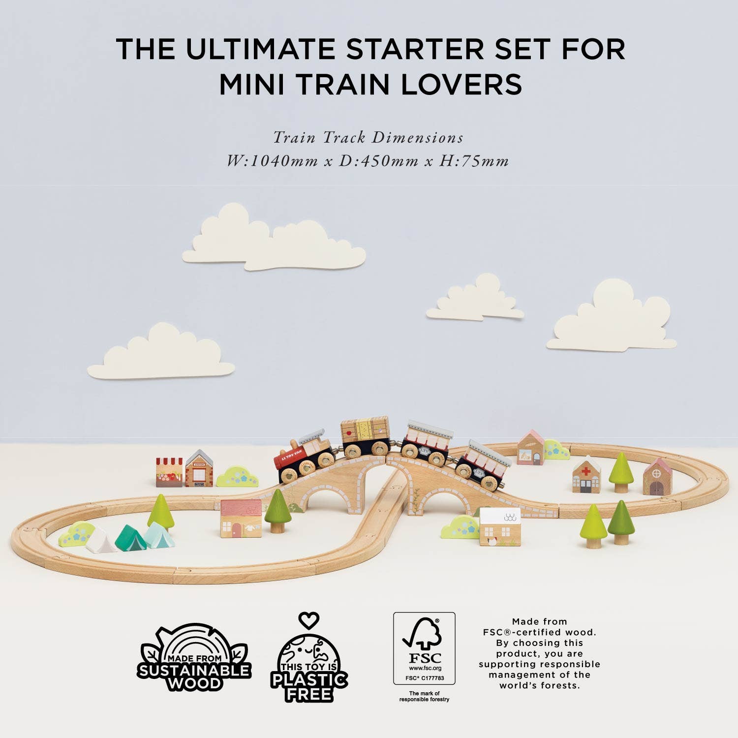 Wooden train set with tracks and small houses on a light blue background with clouds.