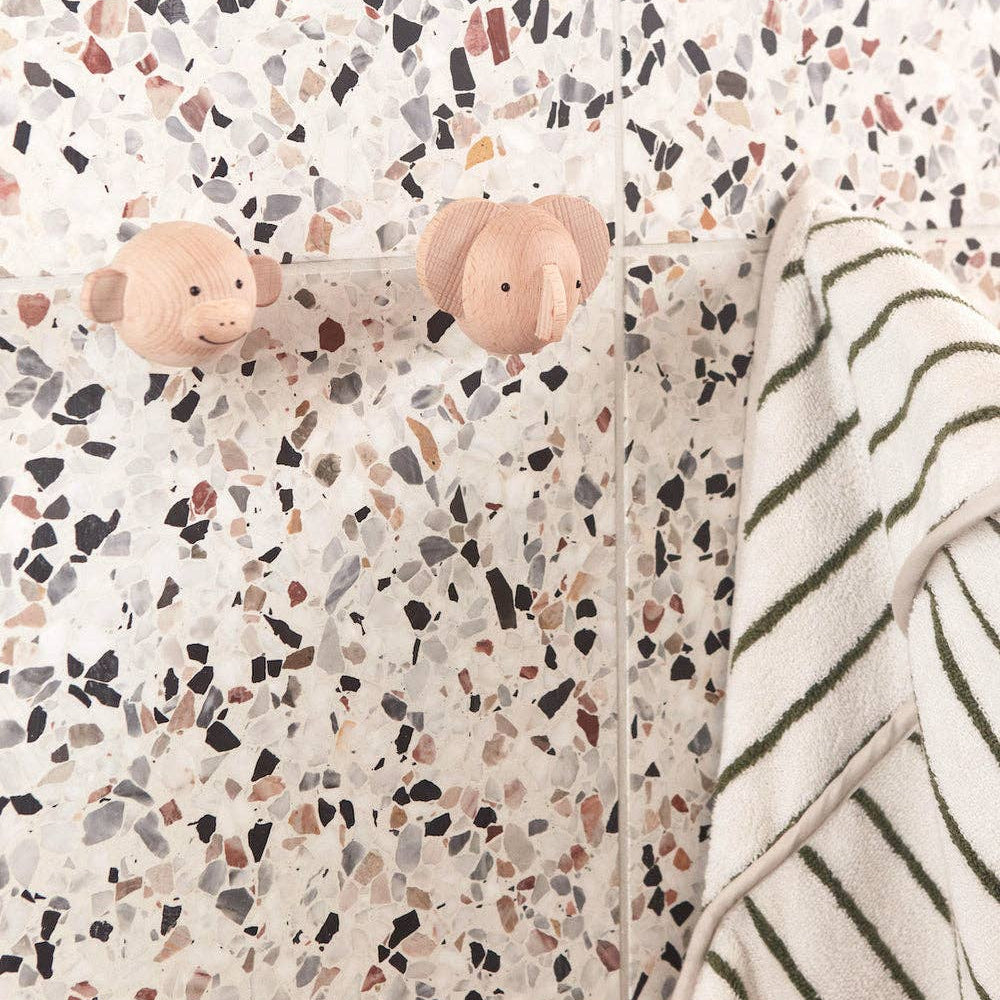 Two pink elephant-shaped hooks on a terrazzo-patterned wall with a striped towel.