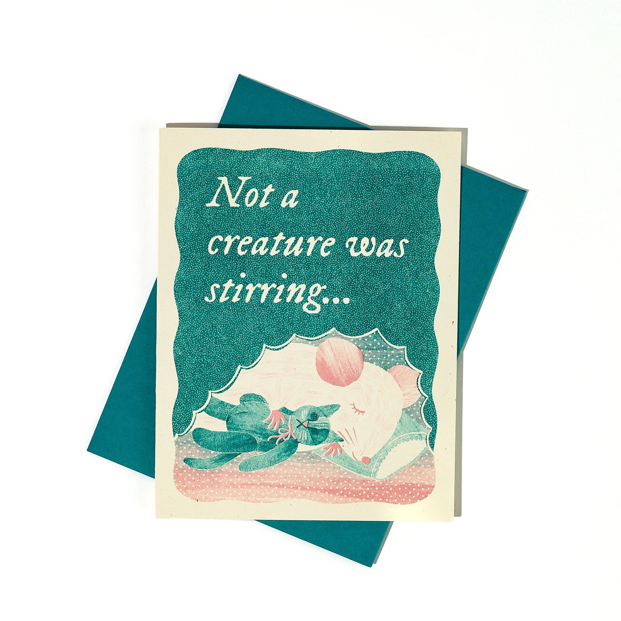 Greeting card with a illustration of a child and a cat under a blanket, text 'Not a creature was stirring', on a teal background.