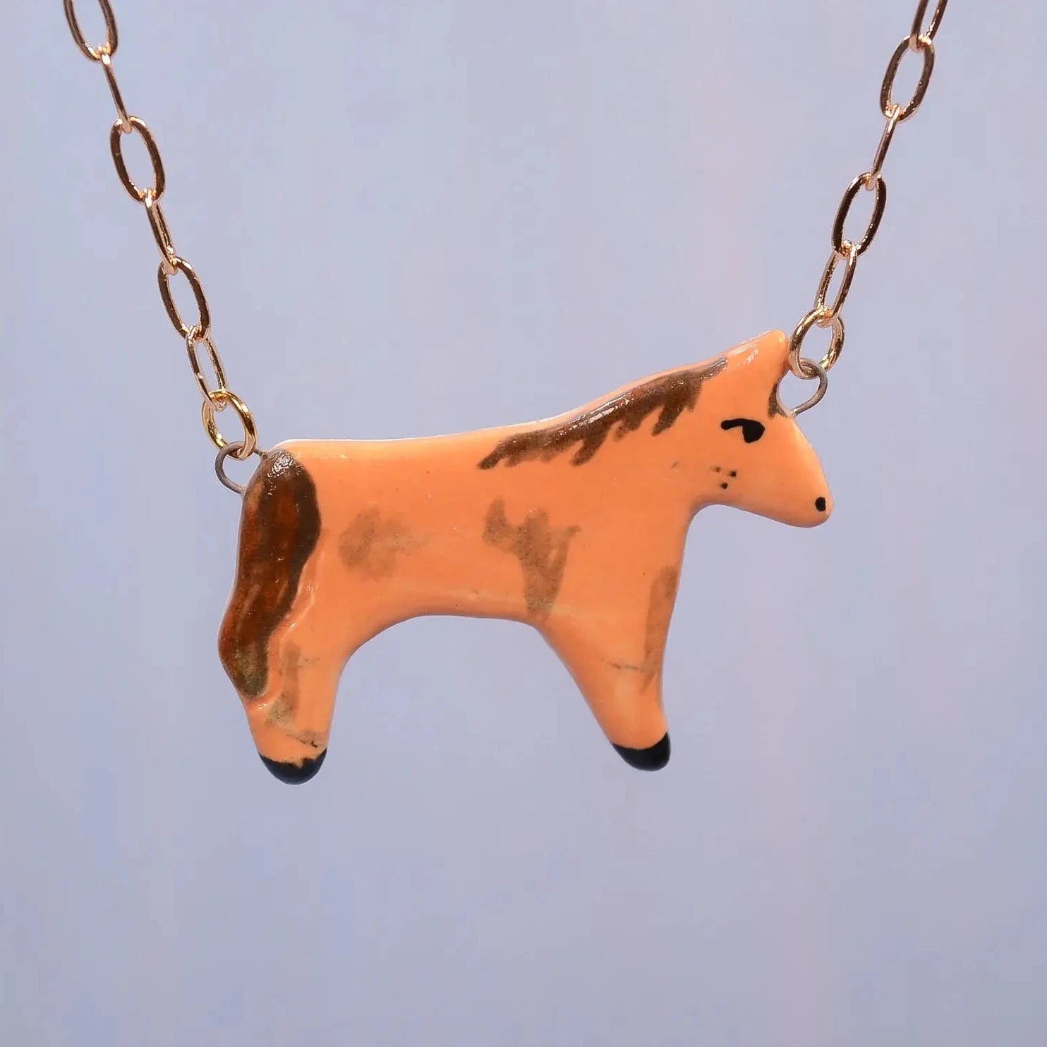 Necklace with a horse-shaped pendant on a light blue background