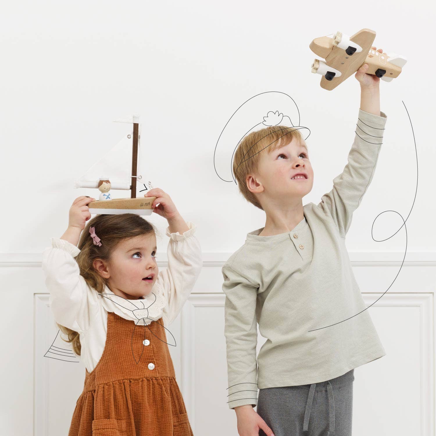 Two children playing with wooden toys against a white wall.