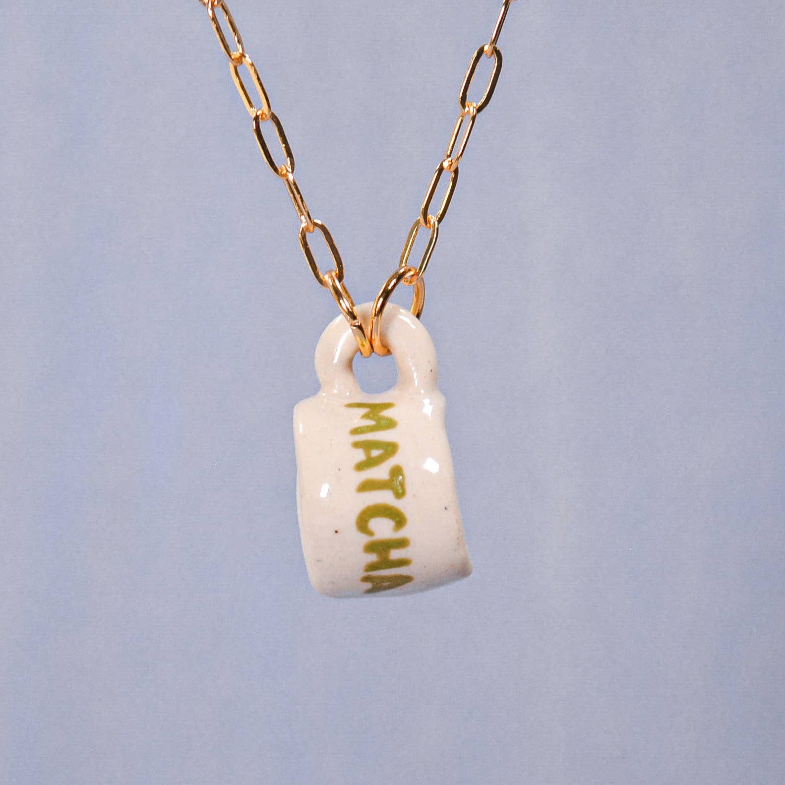 Necklace with a white mug pendant labeled 'Matcha' on a light blue background