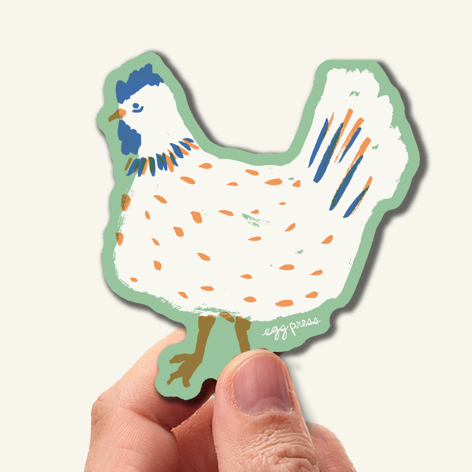 Hand holding a colorful chicken-shaped sticker with a white background