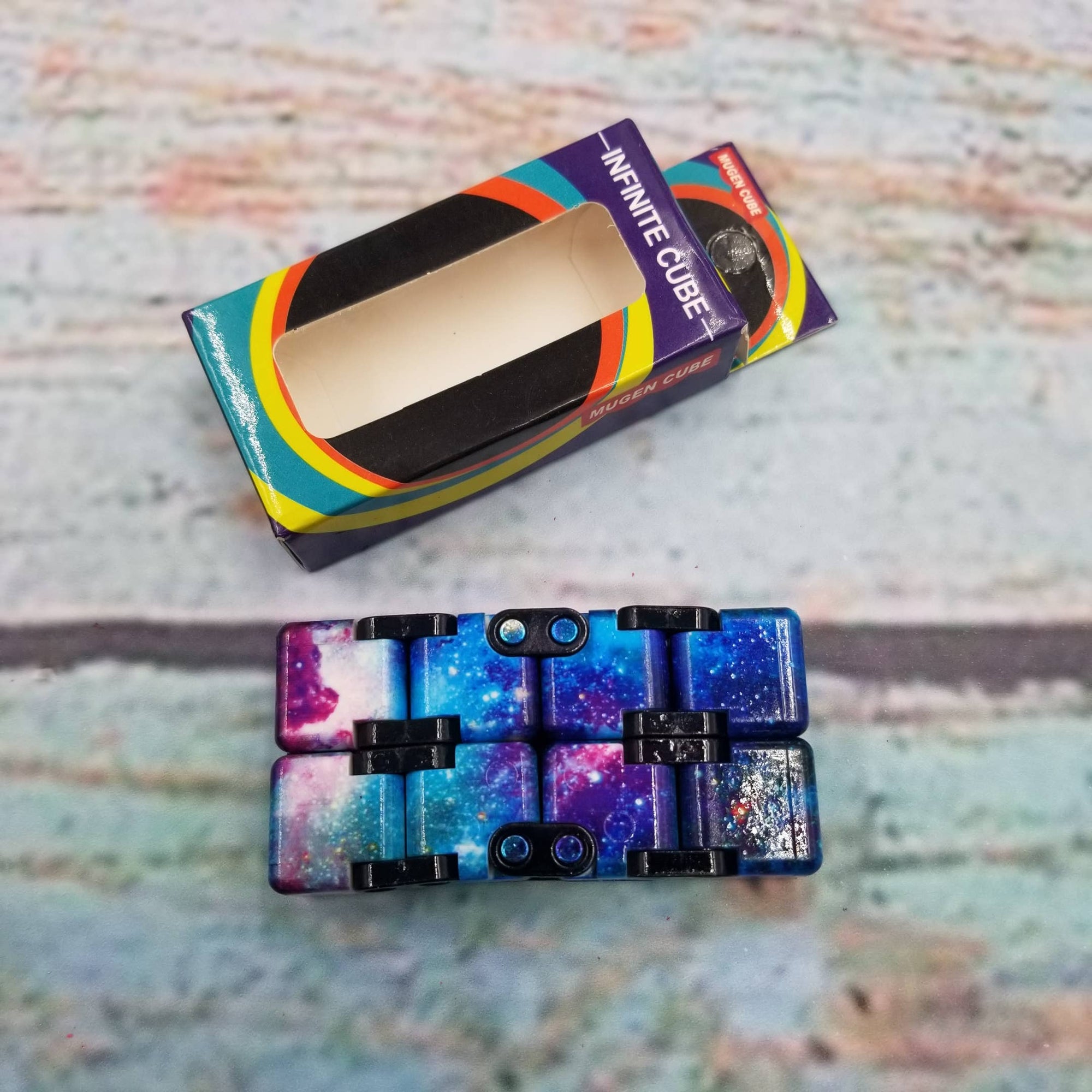 Colorful phone case with 'Infinite Cube' packaging on a textured surface