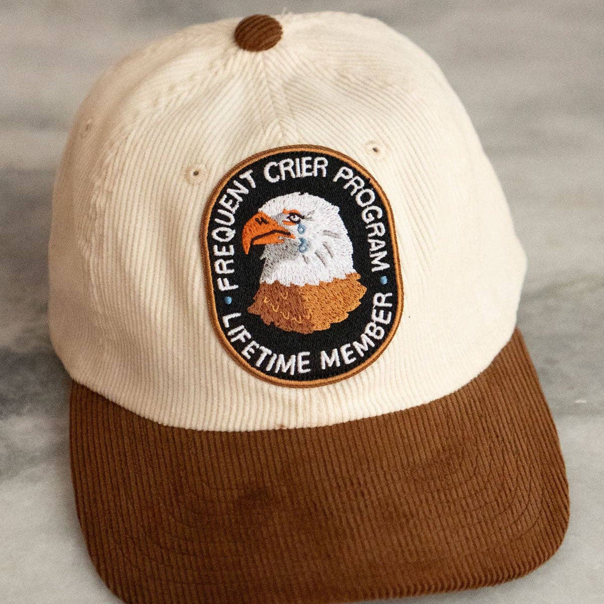 Cap with eagle logo and text on a gray surface