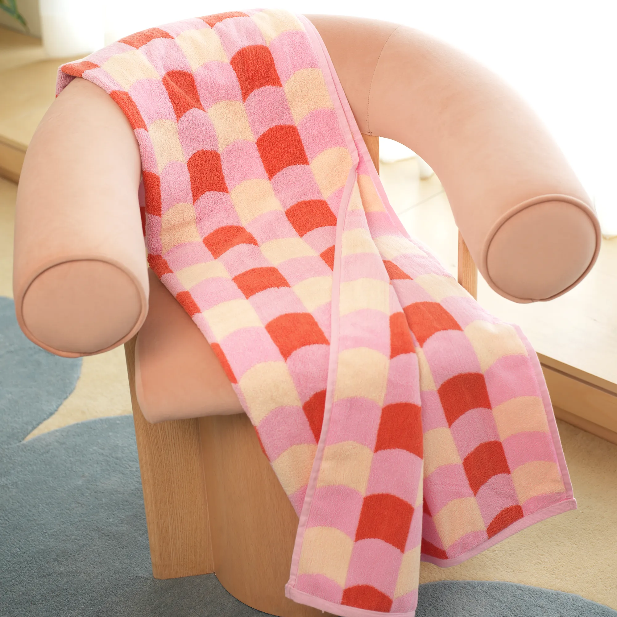 Checkered pink and red blanket draped over a chair