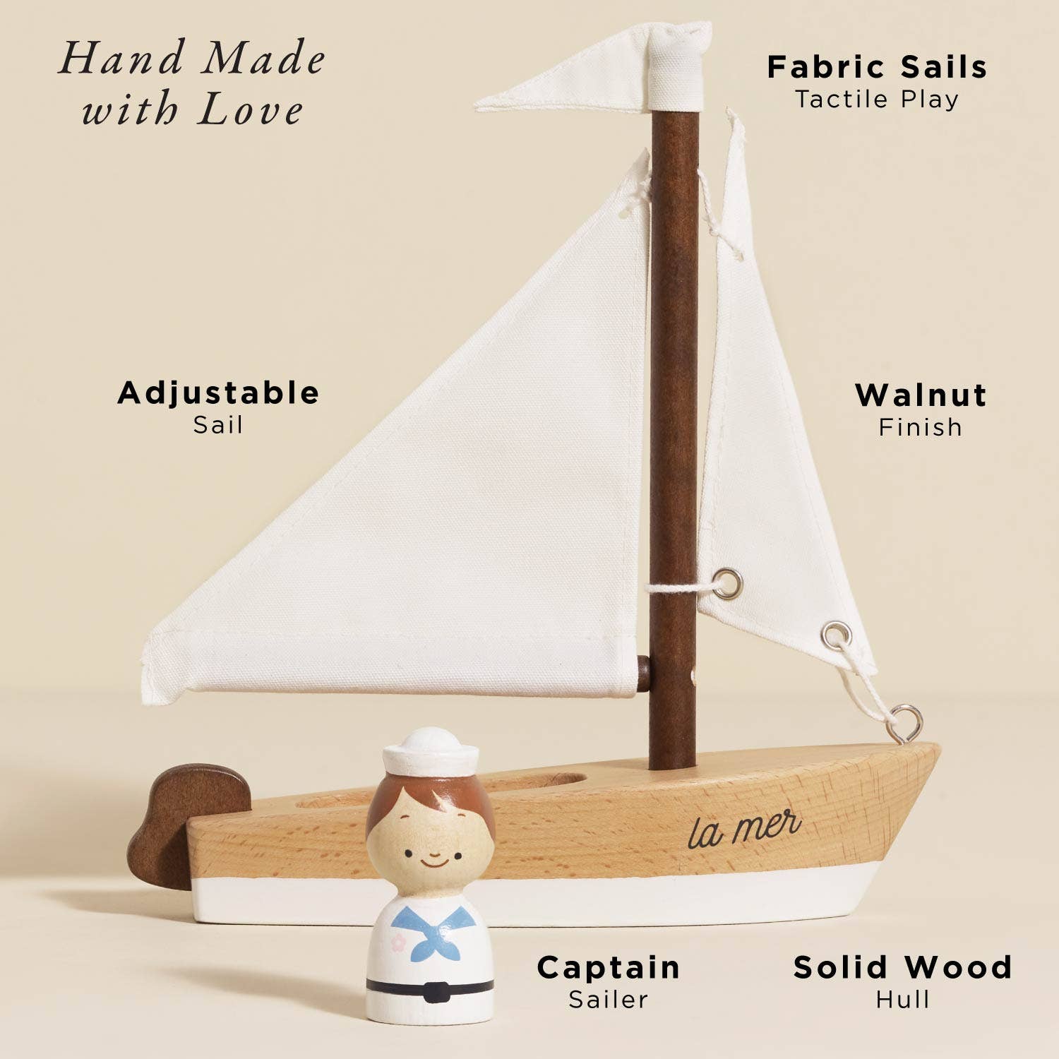 Wooden sailboat with fabric sails and a small figurine of a sailor on a beige background