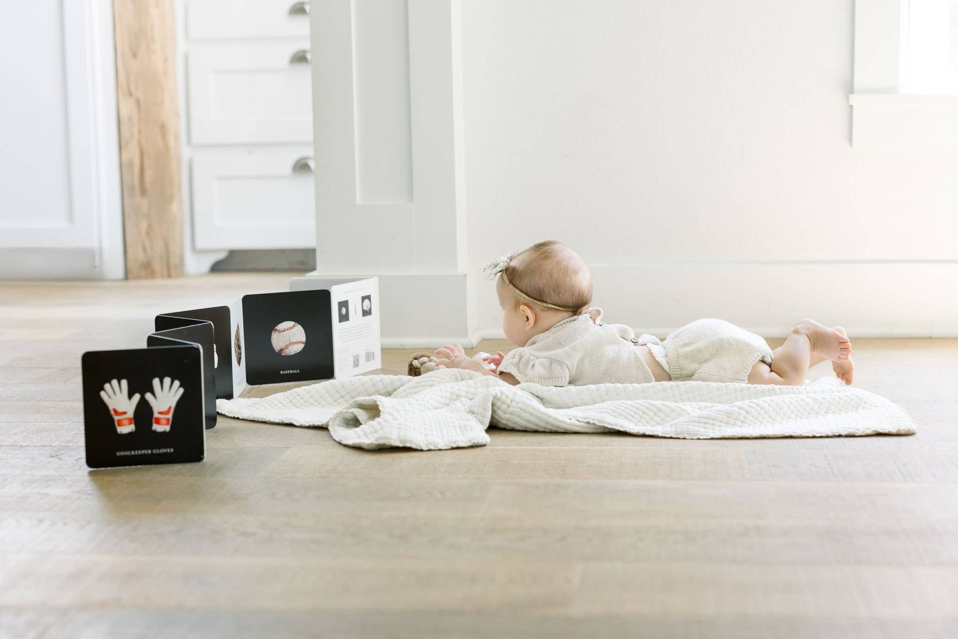 Baby lying on a blanket with educational cards on a wooden floor