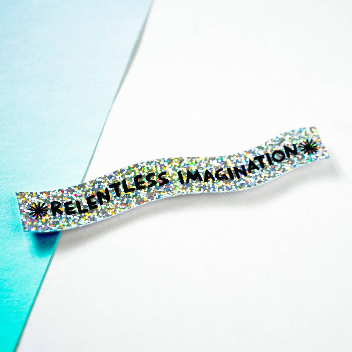 Barrette with 'RELENTLESS IMAGINATION' text on a light blue and white background