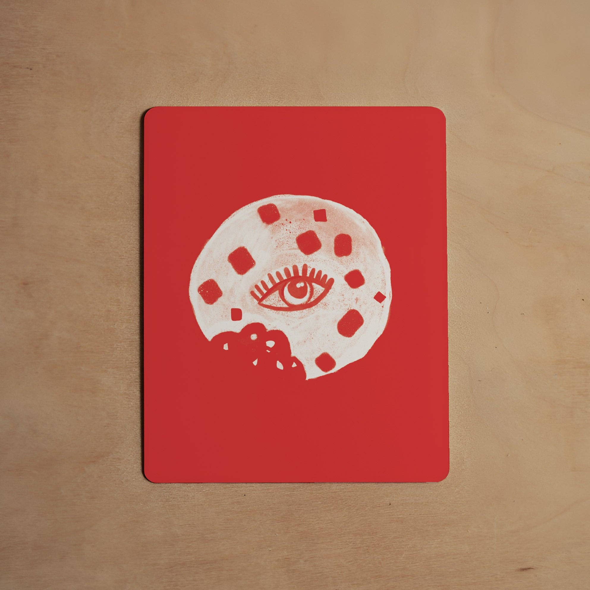 Red card with a white eye design on a wooden surface