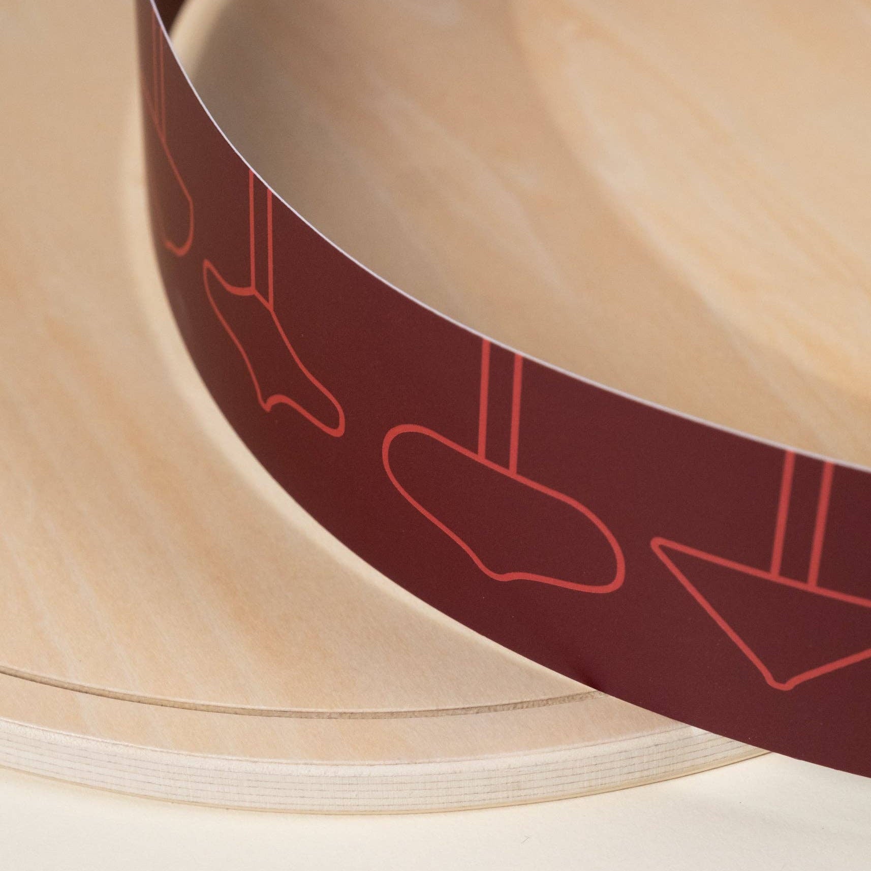 Close-up of a wooden bowl with a red decorative band featuring abstract shapes.