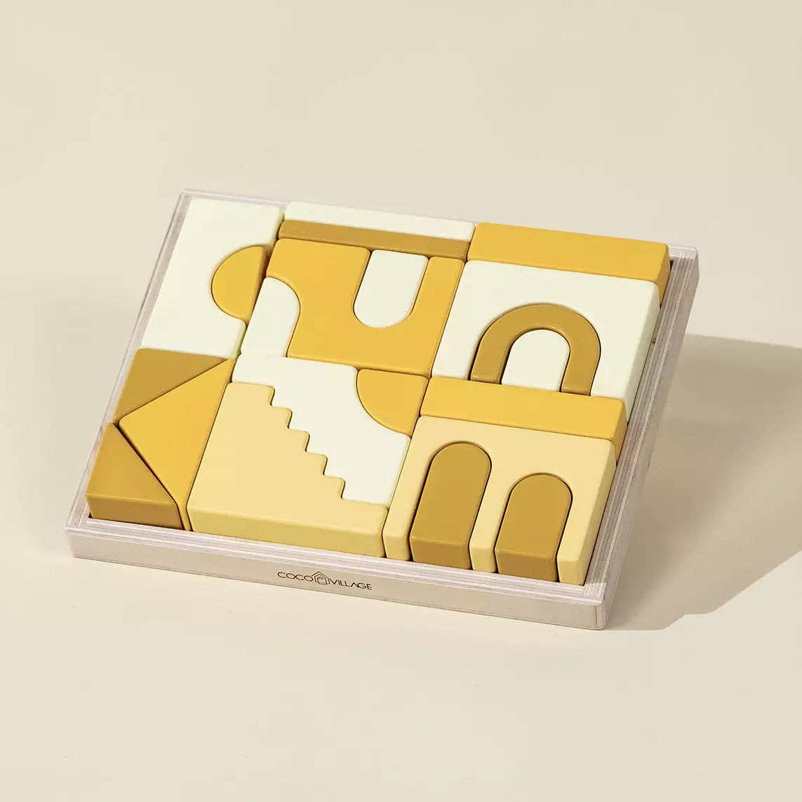 Set of geometric wooden building blocks in a clear box on a beige background