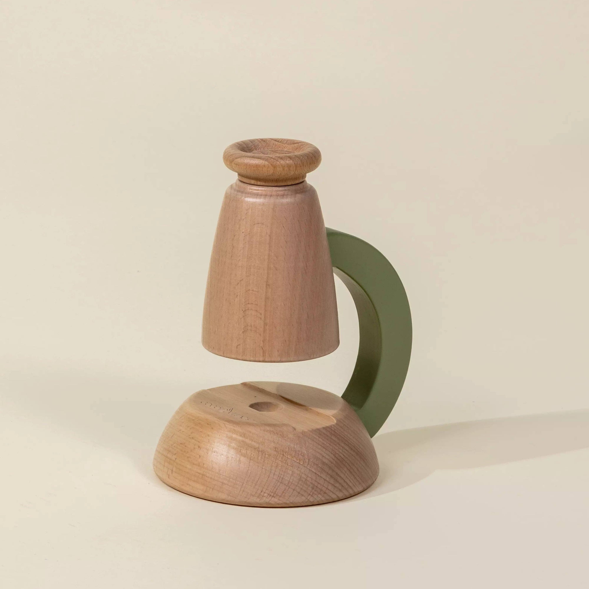 Wooden candle holder with a green handle on a beige background