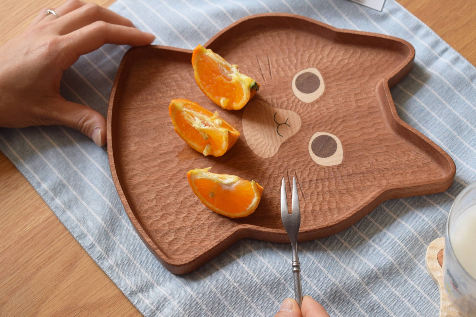 Wooden cat-shaped plate with orange slices on a checkered tablecloth