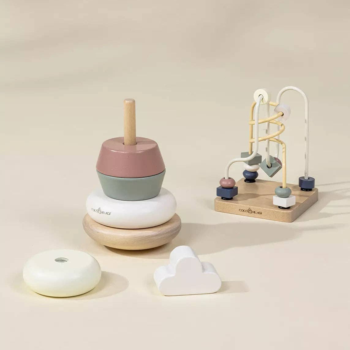 Set of wooden toys including a stacker and a marble run on a beige background