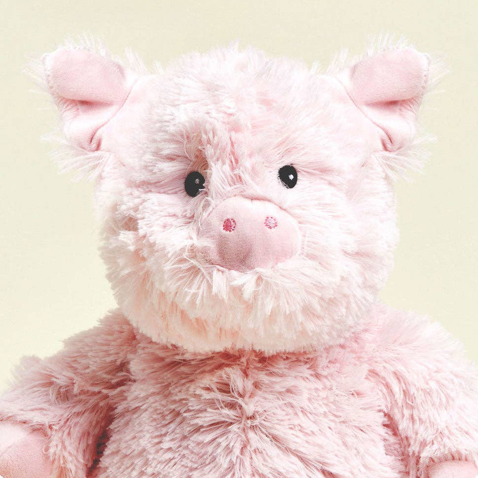 Close-up of a pink plush pig toy on a light green background