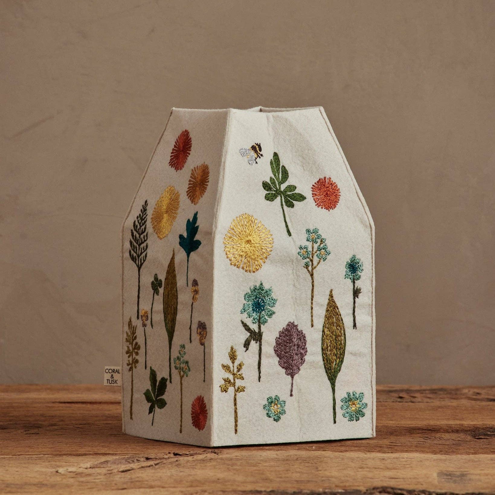 Decorative lampshade with embroidered floral patterns on a wooden surface.
