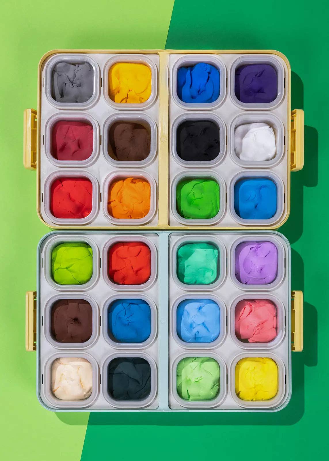 Set of colorful clay blocks in a metal tray on a green background