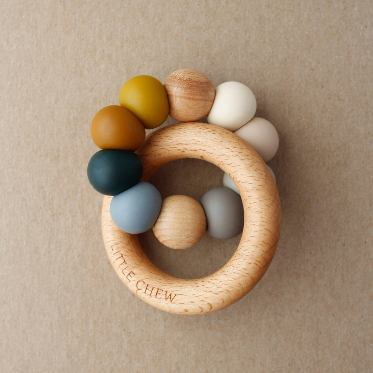 Wooden teething ring with colorful beads on a beige background