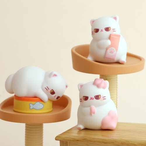 Three cute cat-shaped toys on small platforms with a plain background