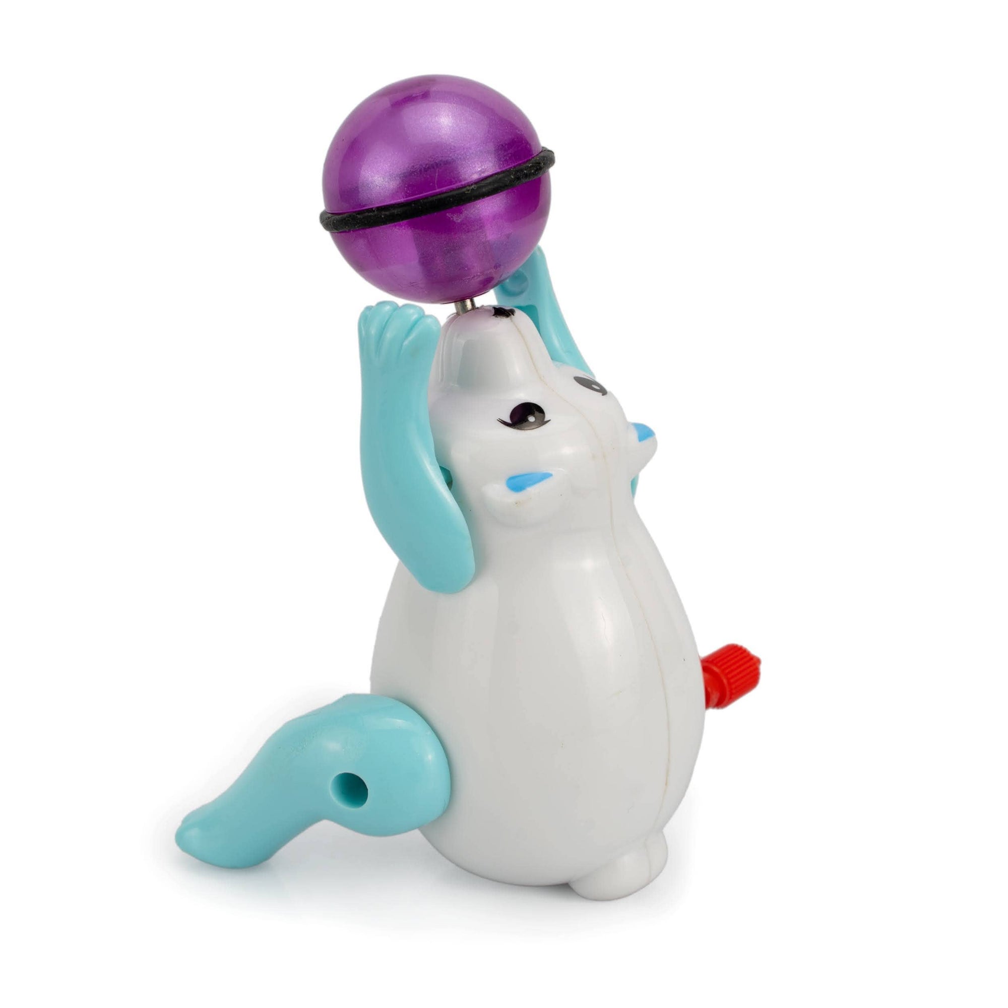 Toy figure of a white animal with blue ears and a purple ball on a white background