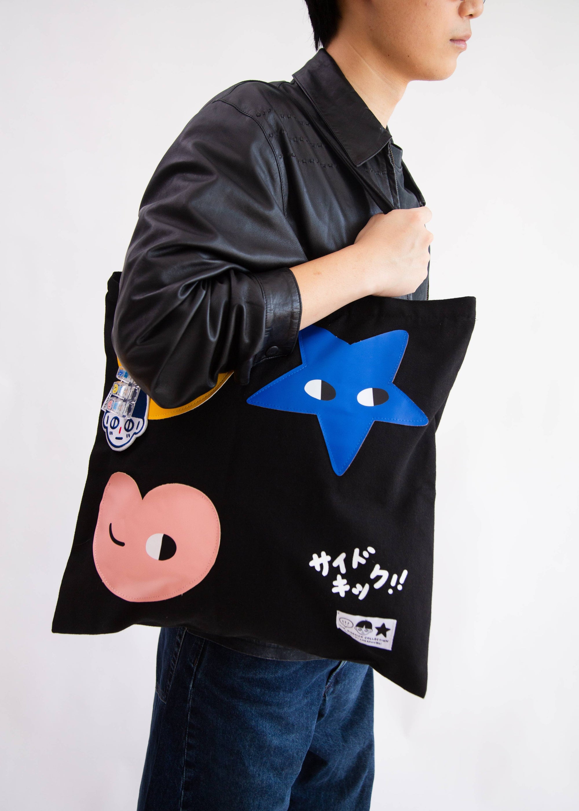Person holding a black tote bag with colorful designs and text.