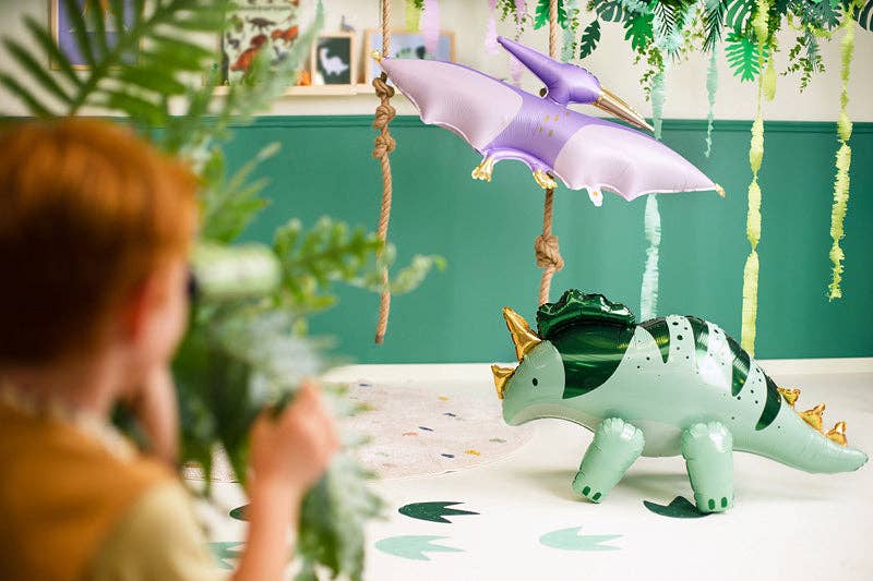 Child playing with dinosaur toys in a room with green walls and plants.