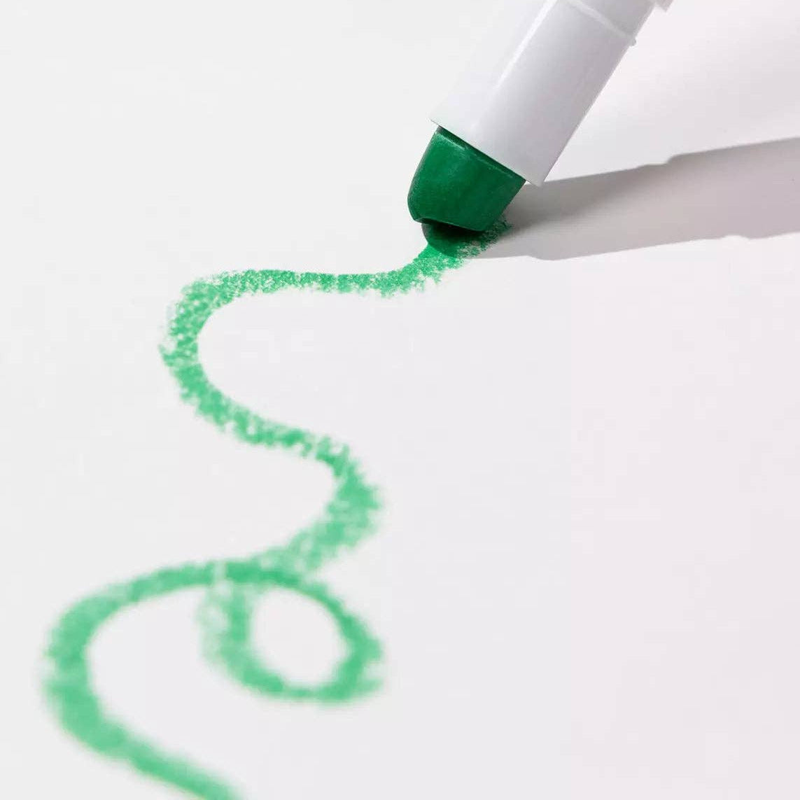 Green marker pen drawing a curved line on white paper