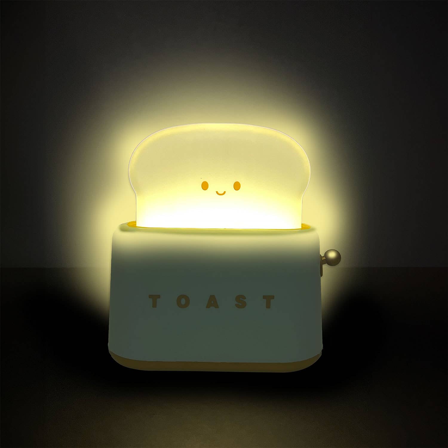 Glowing toy toaster with a smiley face on a dark background