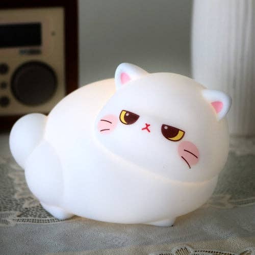 White cat-shaped night light with cartoon face on a textured surface