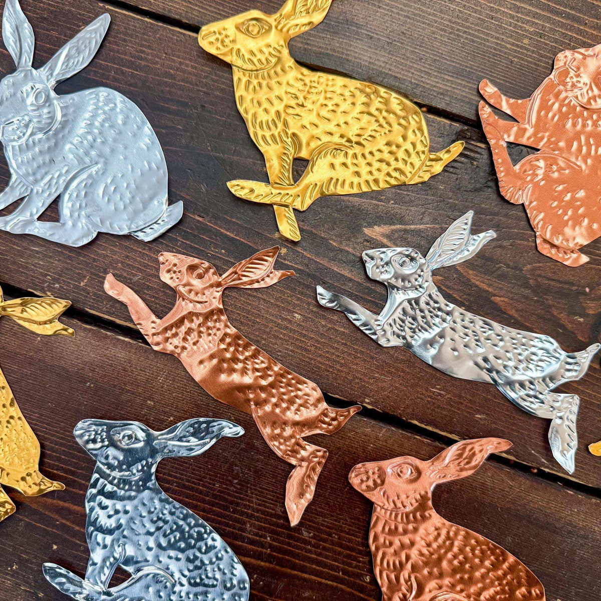 Decorative metal rabbit figurines in various colors on a wooden surface
