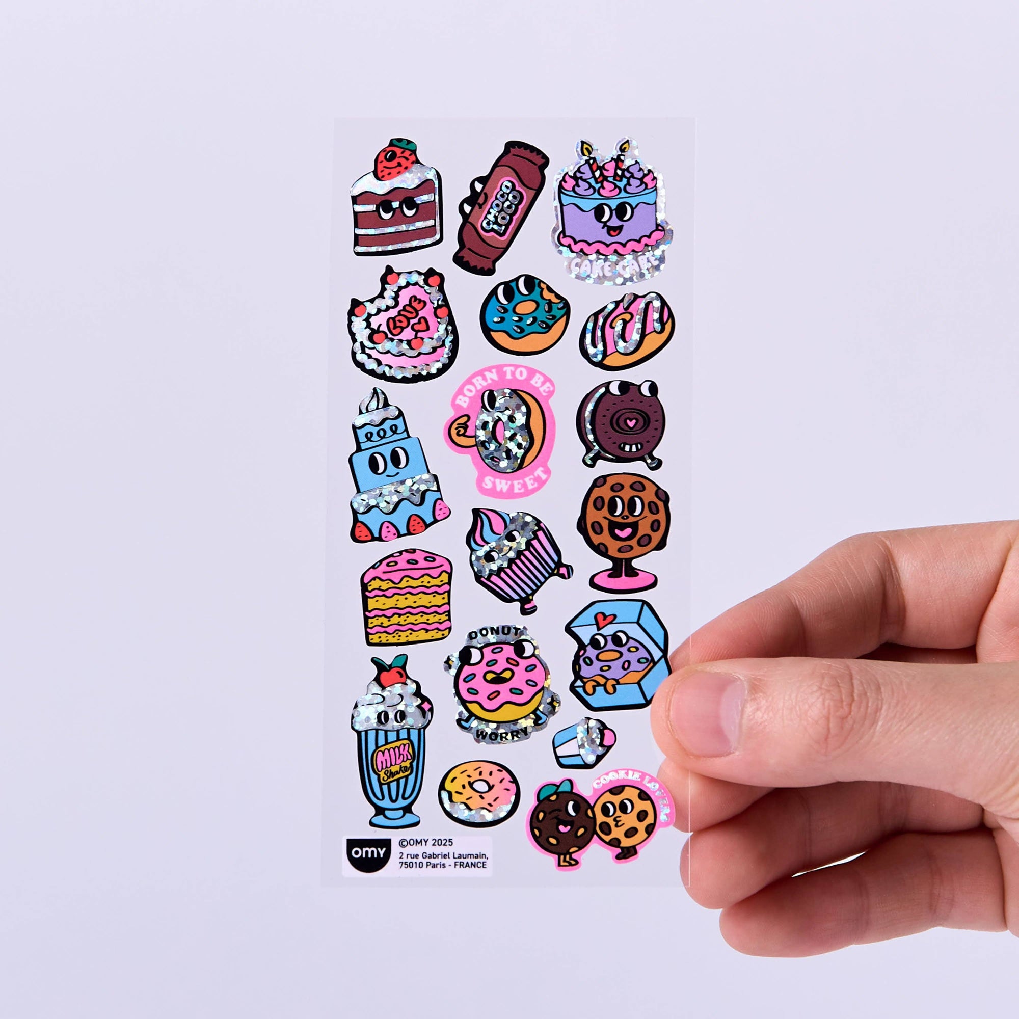 Sheet of colorful cartoon-style stickers held by a hand on a light purple background