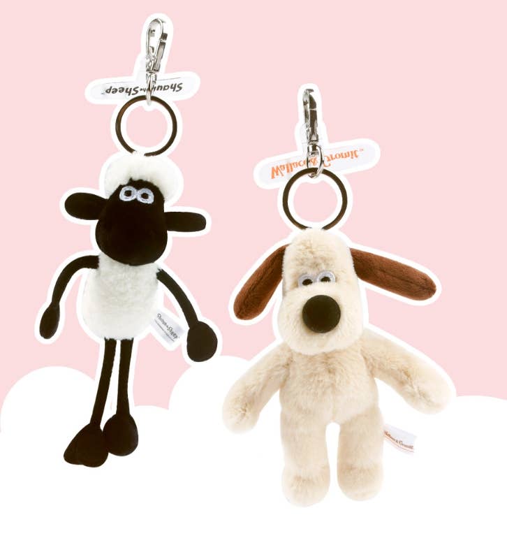Two plush keychains, one sheep and one dog, on a pink background.