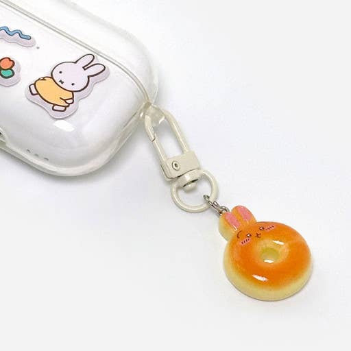Donut-shaped keychain with a rabbit design attached to a clear case on a white background