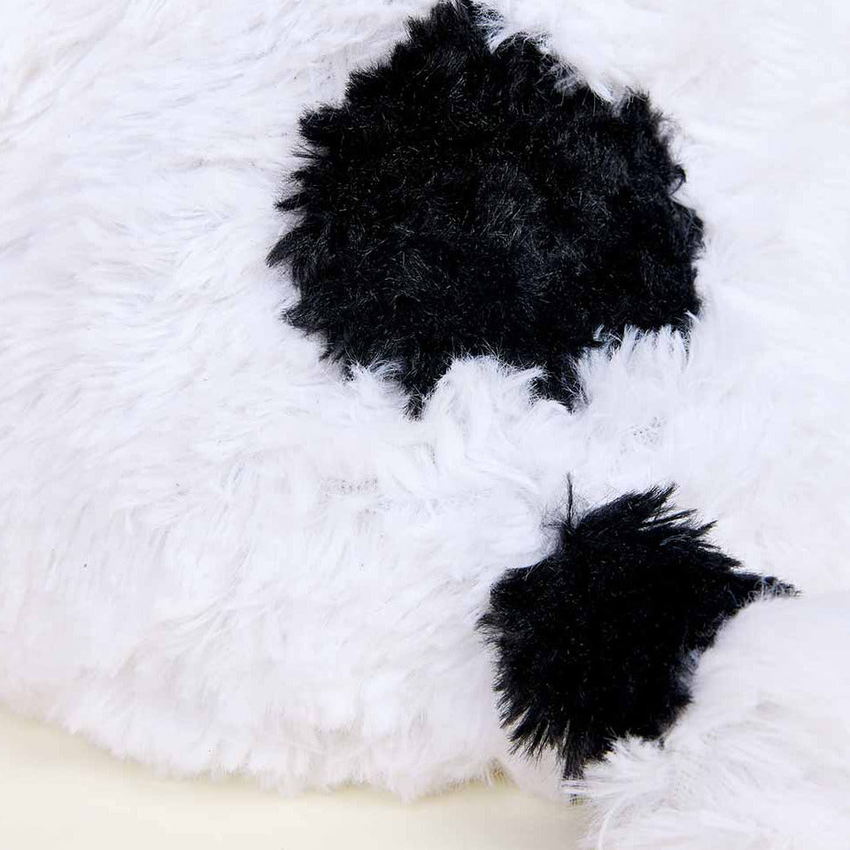 Close-up of a white plush toy with black pom-poms on a white background