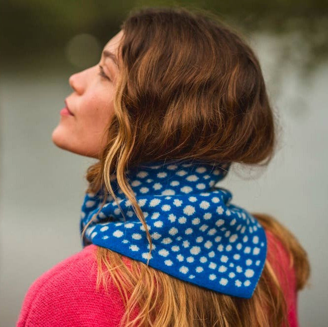 Woman wearing a blue polka dot scarf with a blurred natural background