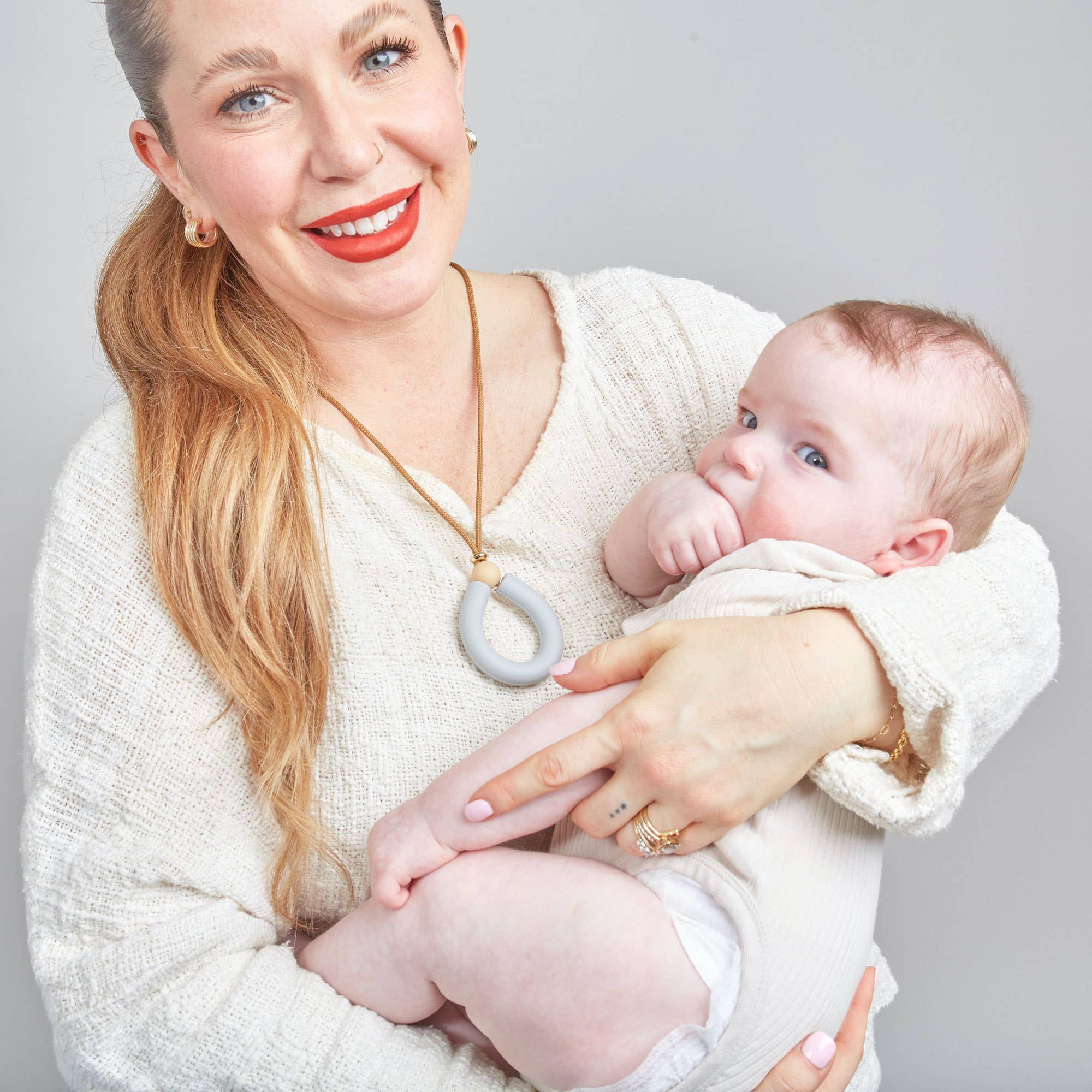 Woman holding a baby against a plain background