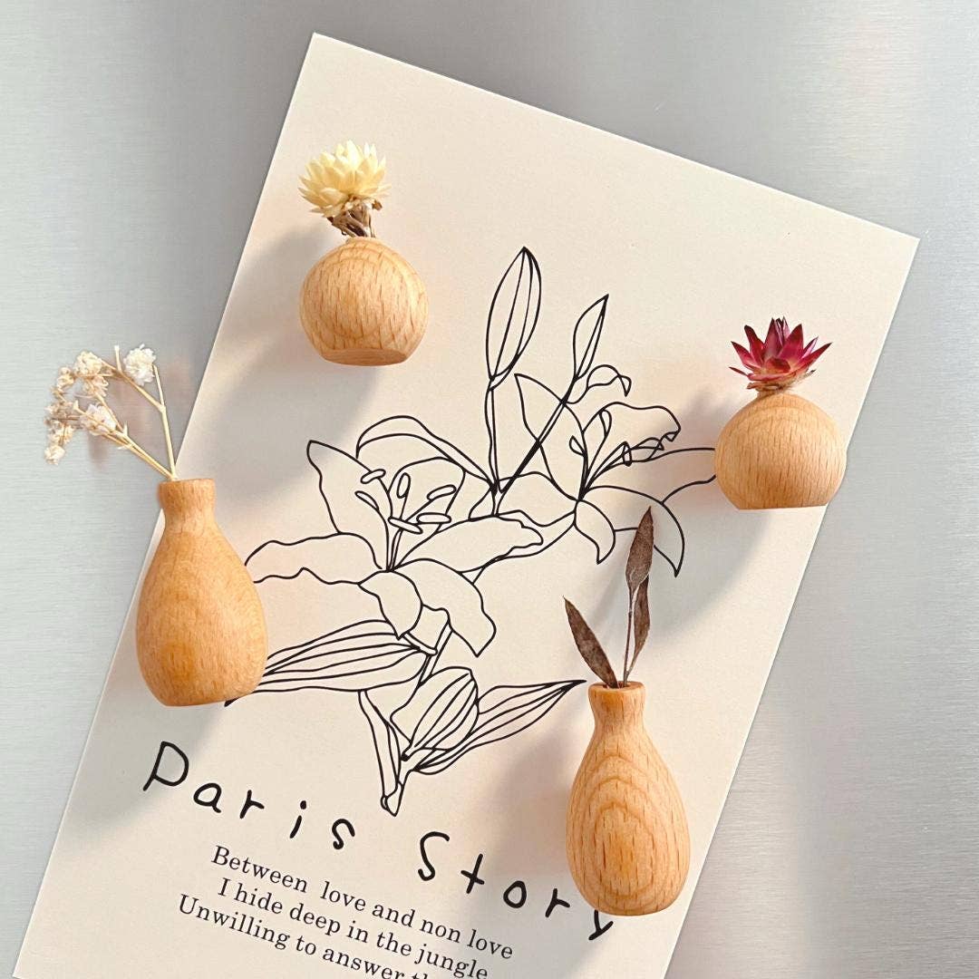 Wooden vases with flowers on a book titled 'Paris Story' with floral illustrations.