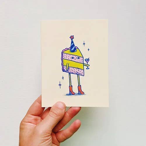 Hand holding a card with a colorful cake illustration against a light cream background