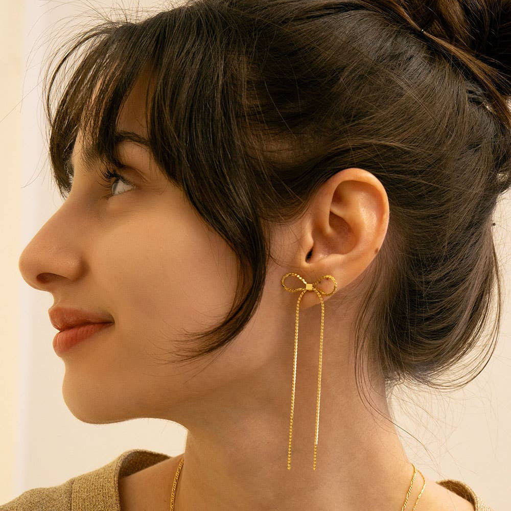 Close-up of a woman wearing gold earrings with a neutral background