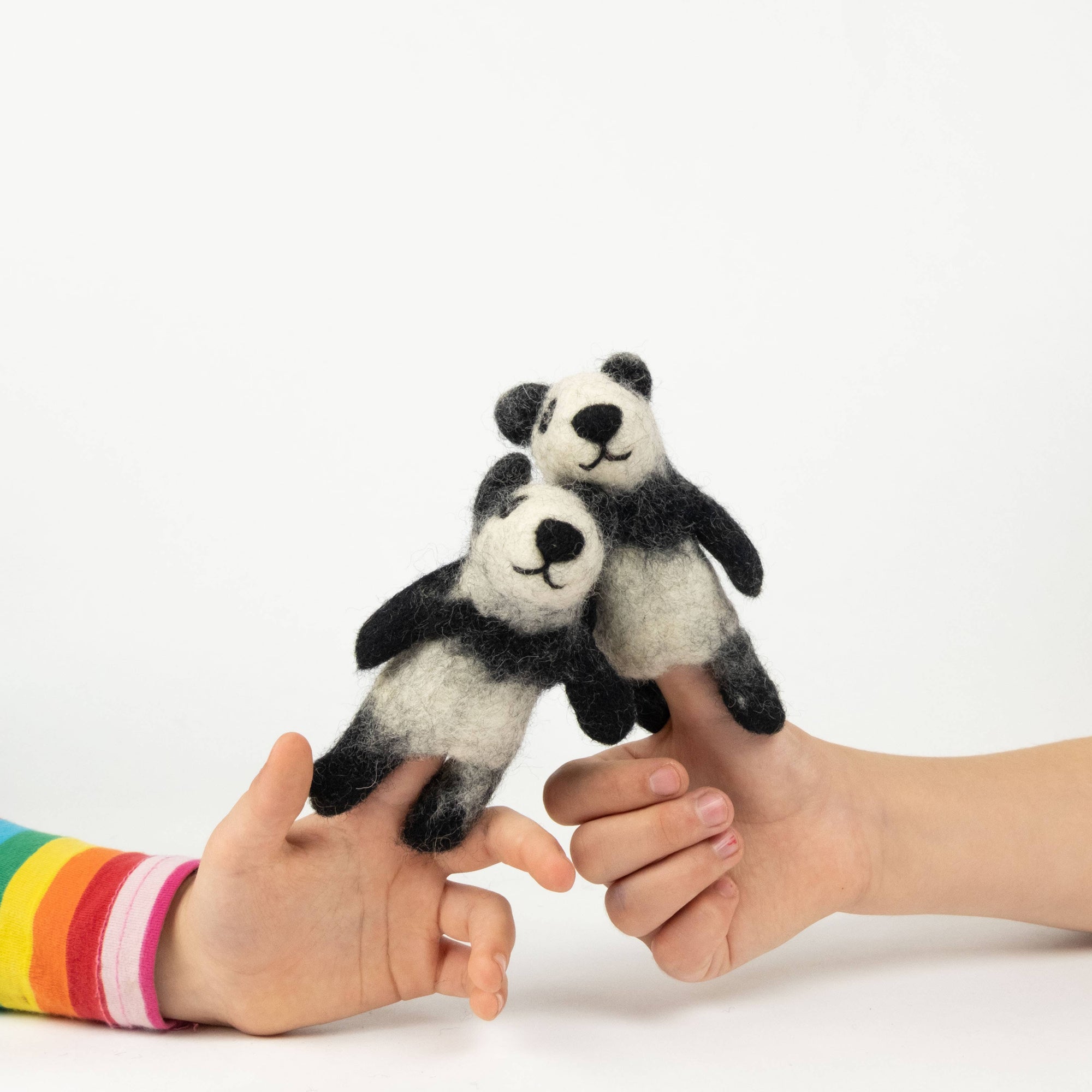 Two panda finger puppets on a person's fingers against a white background
