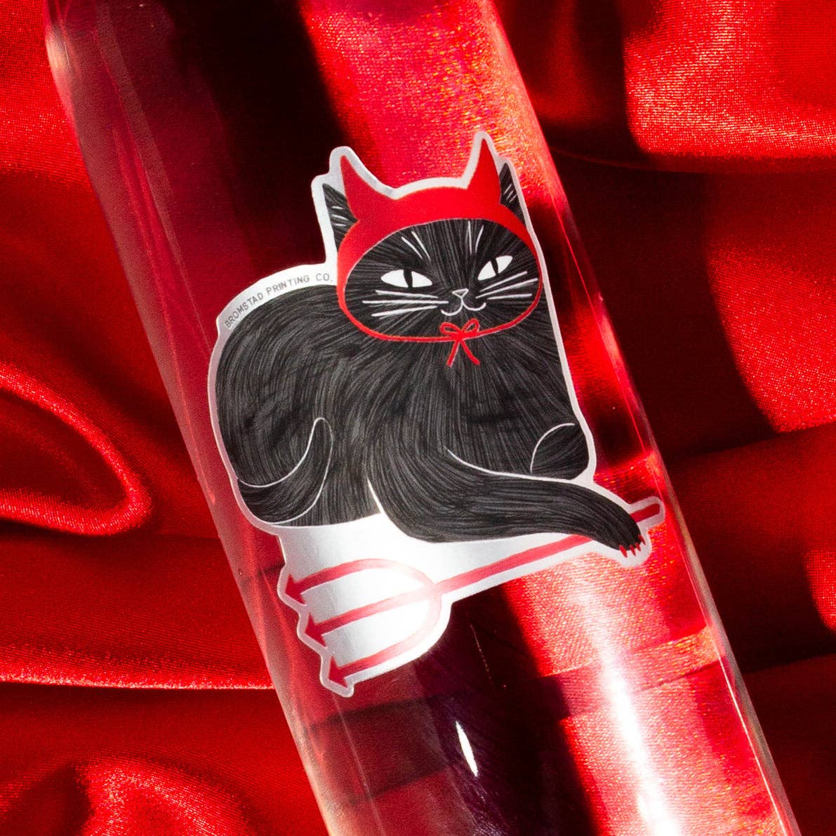 Clear pen with black cat in red hood design on a red background