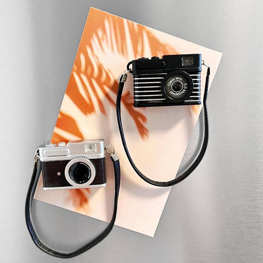 Two vintage-style cameras with straps on a tie-dye fabric background