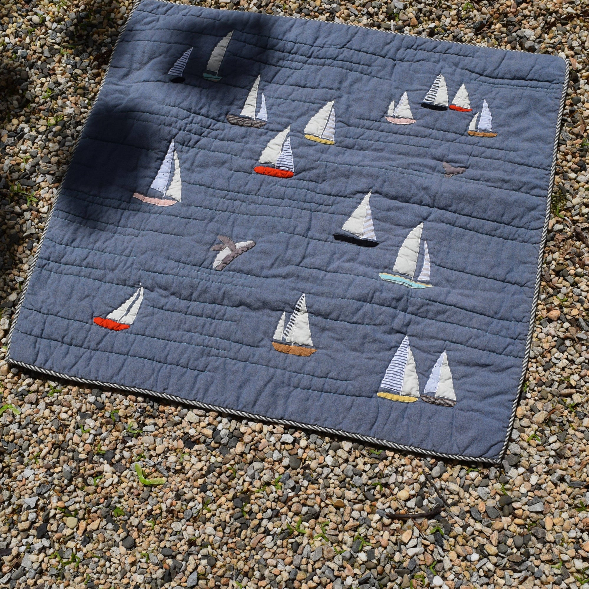 Quilt with sailboat pattern on a gravel surface