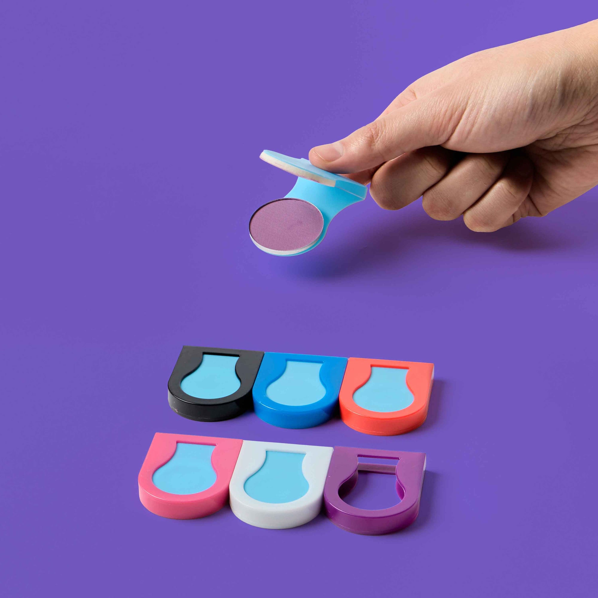 Hand holding a colorful object against a purple background