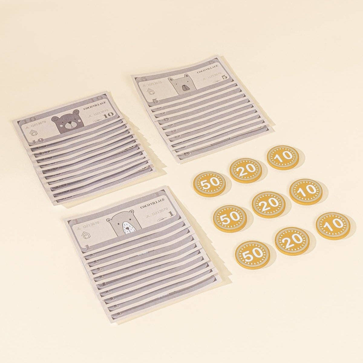 Three play cash bills with a bear design on a beige background, accompanied by gold coins with numbers.