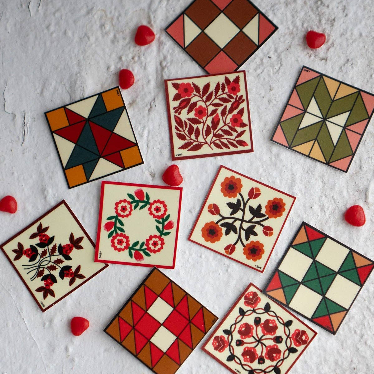 Decorative square tiles with floral and geometric patterns on a textured surface.